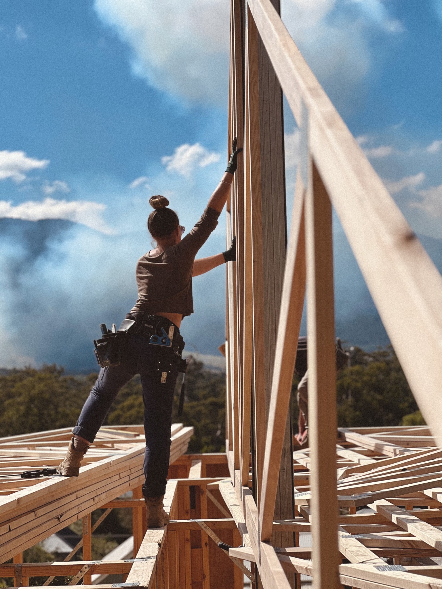 Naomi Lee O’Brien working on timber wall framing against a mountain landscape